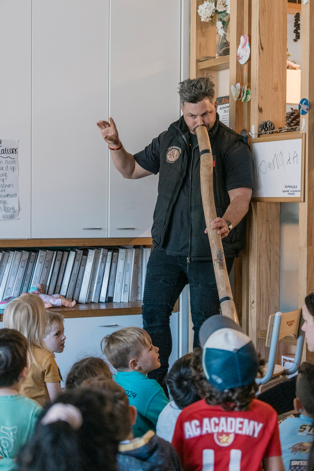 Man standing up playing digeridoo to the classroom