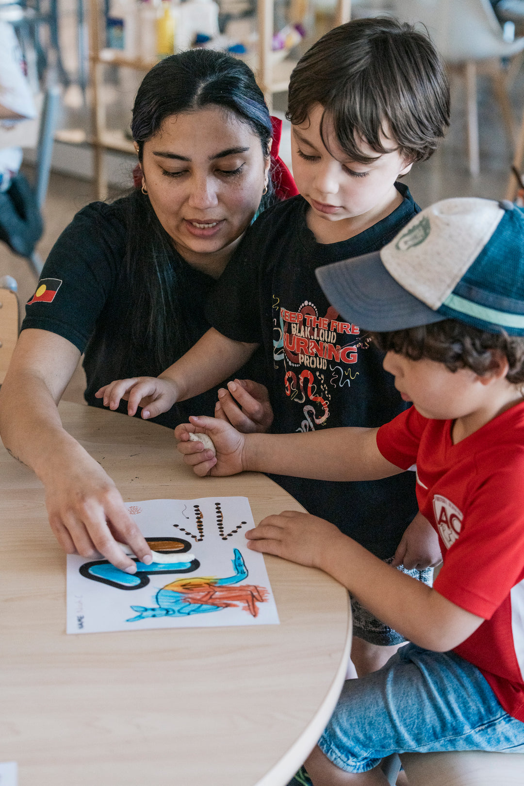 Woman helping children create art on the colouring paper.